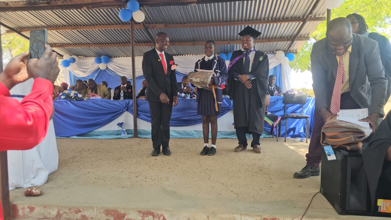 THE HEAD MR ZVIDZAI ISSUING PRIZES TO A LEARNER. PGD 2026